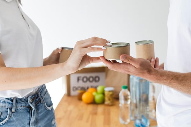 A close-up shot of hands placing canned goods into a food box, with a blurred background showing other volunteers and food items. The focus is on the act of giving and providing sustenance.