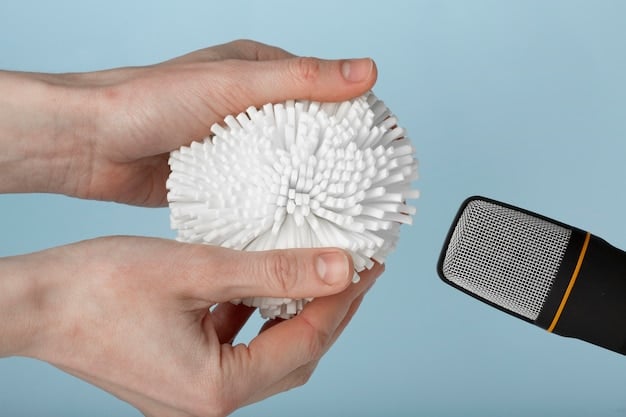 A person carefully cleaning a smart speaker with a soft brush and a microfiber cloth. The speaker is placed on a desk with other smart home devices in the background. The lighting is soft and diffused, highlighting the cleaning process.