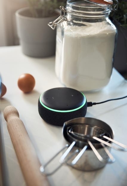 A close-up shot of an Amazon Echo device on a kitchen countertop. The device is displaying a recipe on its screen, illustrating its utility in the kitchen. Soft, natural light highlights the device and the surrounding countertop.