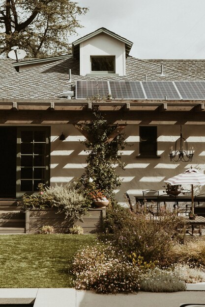 An outdoor shot of a house with solar panels on the roof and a smart irrigation system in the garden, illustrating comprehensive smart home energy solutions.
