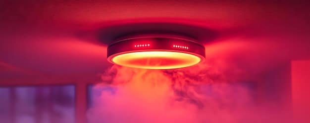 A close-up of a smart smoke detector mounted on a ceiling, showcasing its sleek design and the LED indicator light. The focus is on the advanced technology embedded in the device.