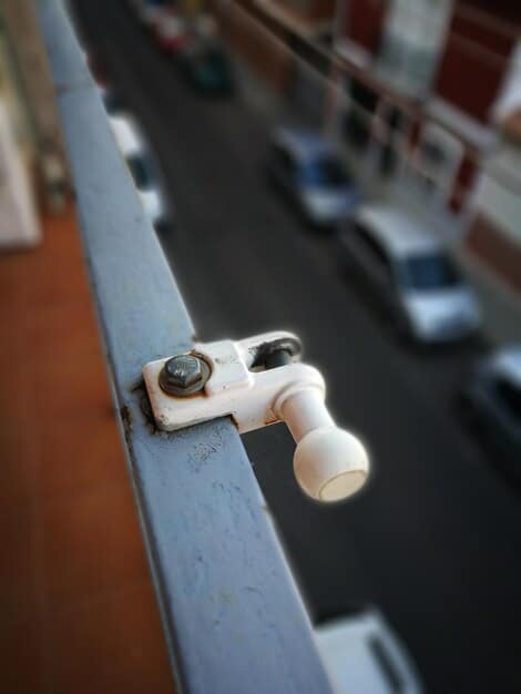 A close-up shot of a reinforced garage door lock with heavy-duty bolts, emphasizing its strength and tamper-resistance. The background shows a blurred garage door panel with additional reinforcement.